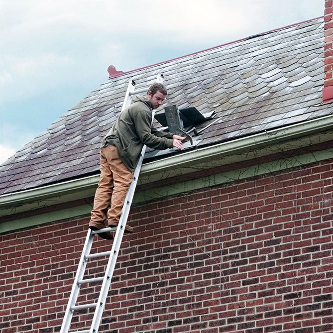 Man fixing a broken roof tile